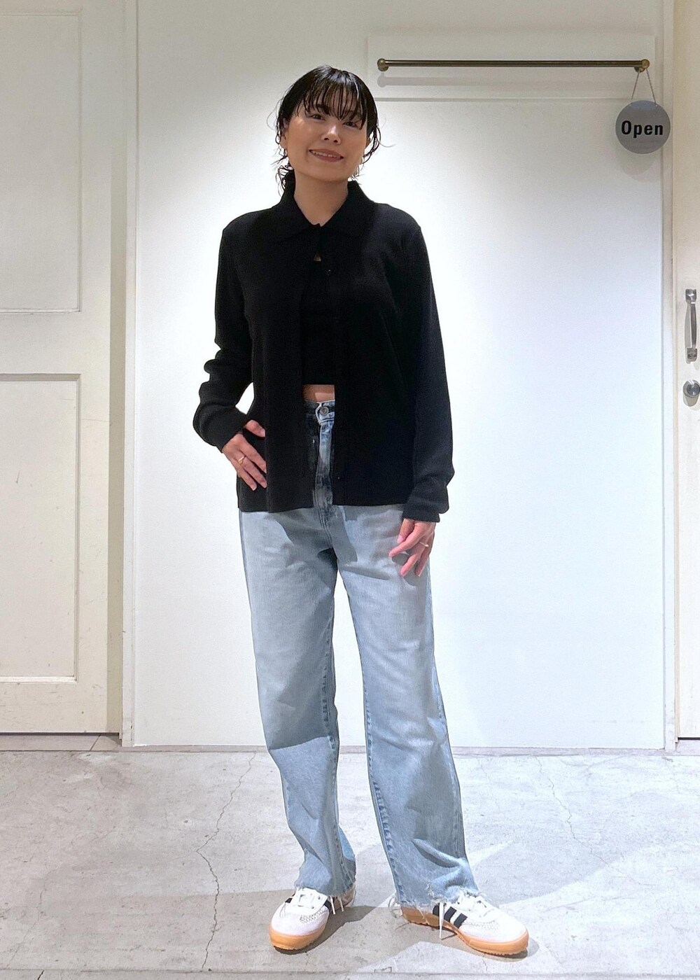 ブラック系のカーディガン/ボレロ、ホワイト系のスニーカー、ブルー系のデニムパンツを着用したレディースの夏コーディネートの2枚目の写真