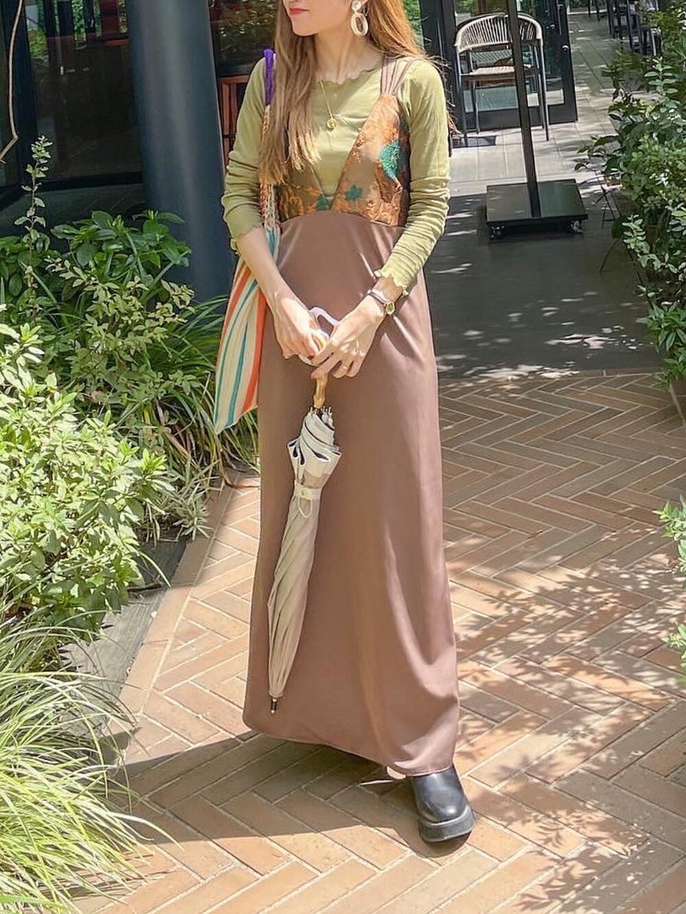 ブラウン系のワンピース、ベージュ系のバッグ、グリーン系のTシャツ/カットソーを着用したレディースの秋コーディネートの2枚目の写真