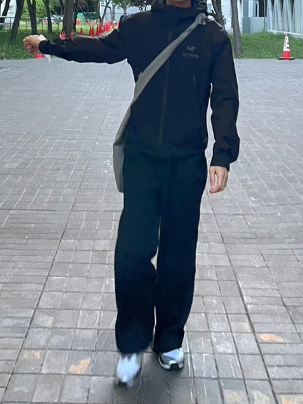 ブラック系のスニーカー、ブラック系のブルゾン、グレー系のショルダーバッグを着用したメンズの夏コーディネートの2枚目の写真