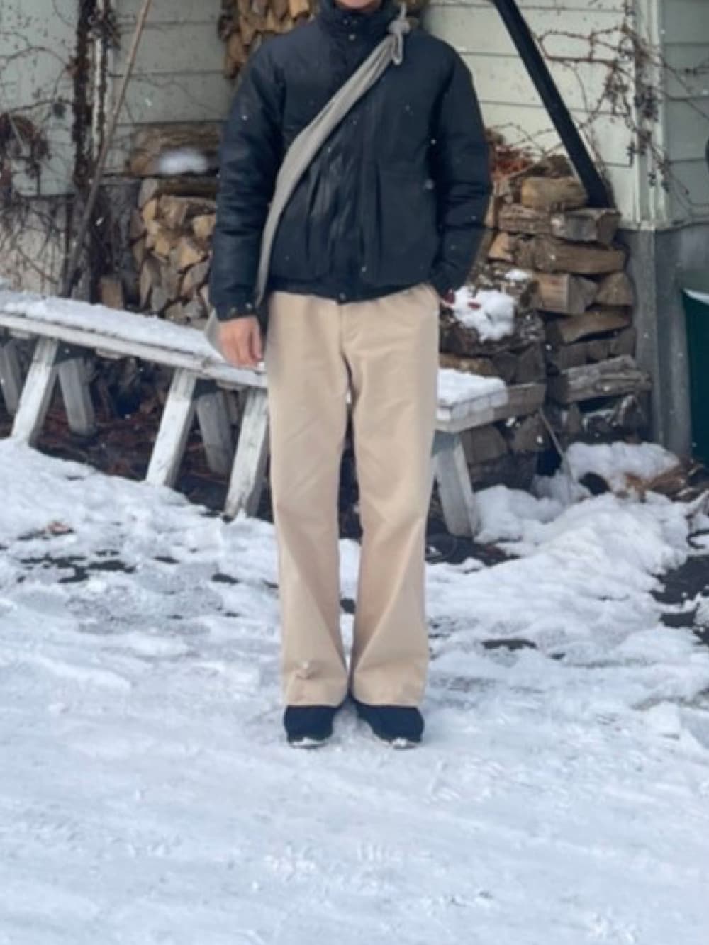 ブラック系のダウンジャケット/コート、グレー系のショルダーバッグ、ベージュ系のチノパンツを着用したメンズの冬コーディネートの2枚目の写真