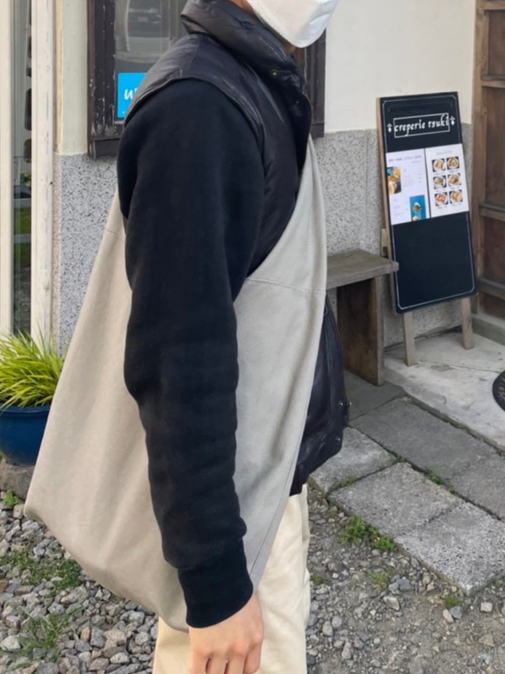 ベージュ系のチノパンツ、ブラウン系のダウンベスト、ブラック系のスウェットを着用したメンズの夏コーディネートの2枚目の写真