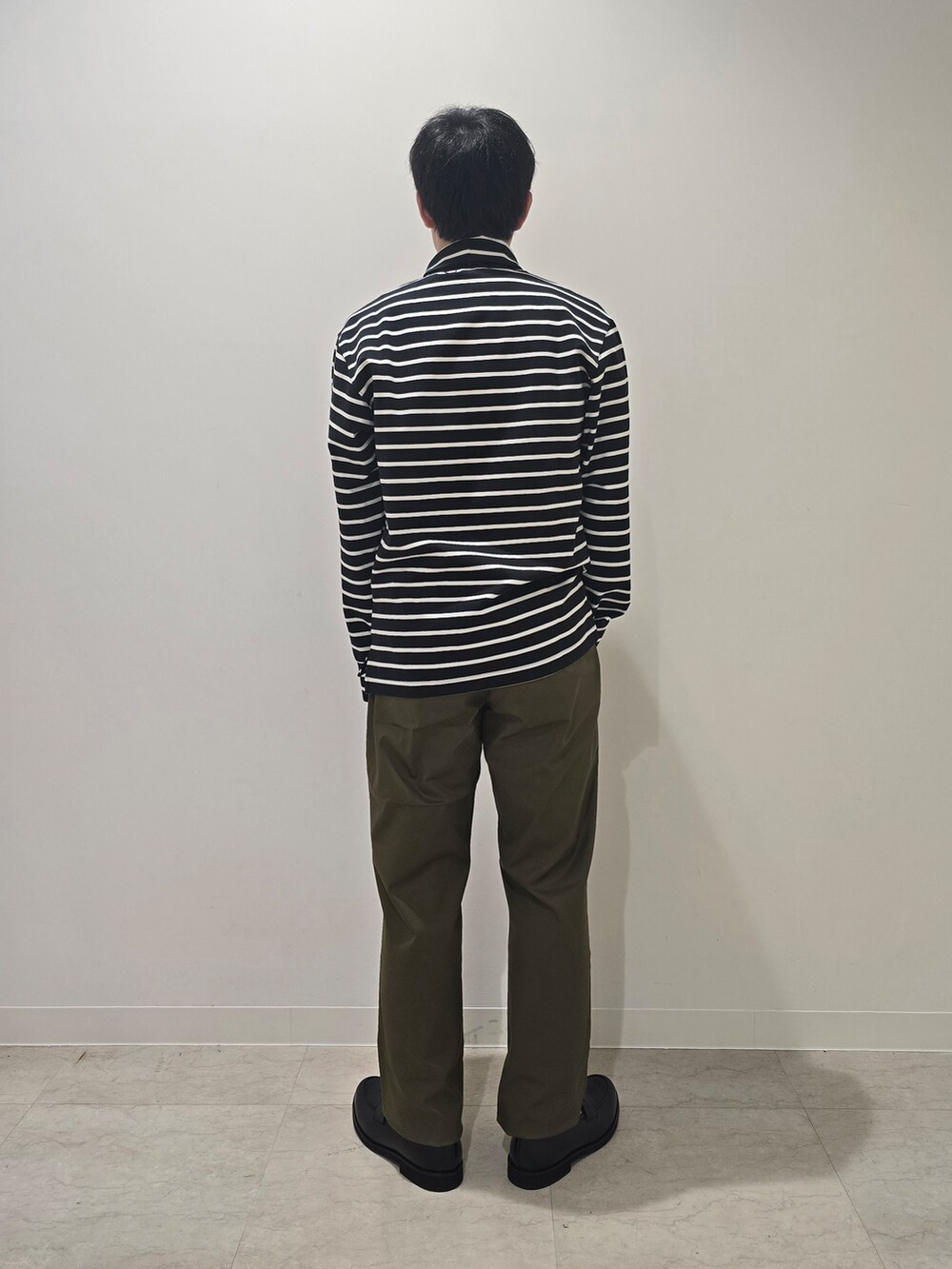 グリーン系のスラックス、ブラック系のTシャツ/カットソー、ブラック系のドレスシューズを着用したメンズの秋コーディネートの6枚目の写真