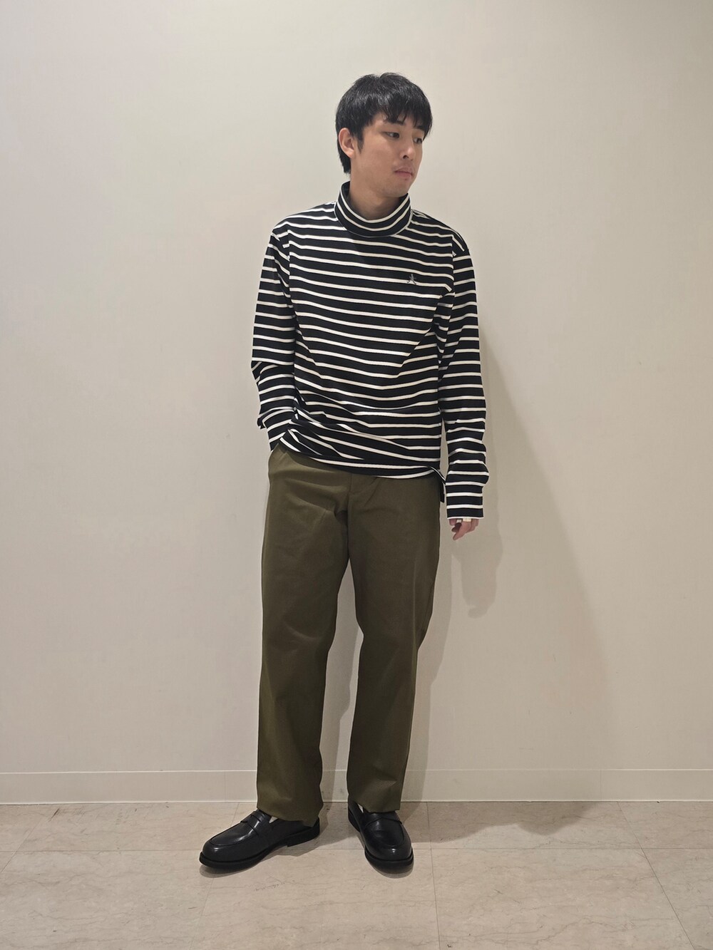 グリーン系のスラックス、ブラック系のTシャツ/カットソー、ブラック系のドレスシューズを着用したメンズの秋コーディネートの3枚目の写真