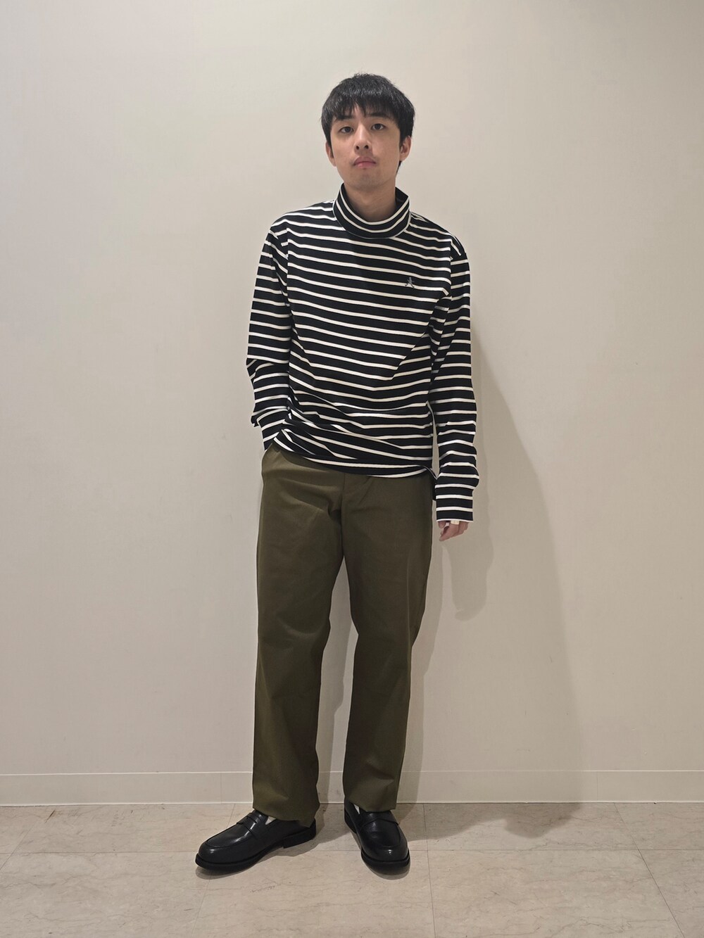 グリーン系のスラックス、ブラック系のTシャツ/カットソー、ブラック系のドレスシューズを着用したメンズの秋コーディネートの2枚目の写真