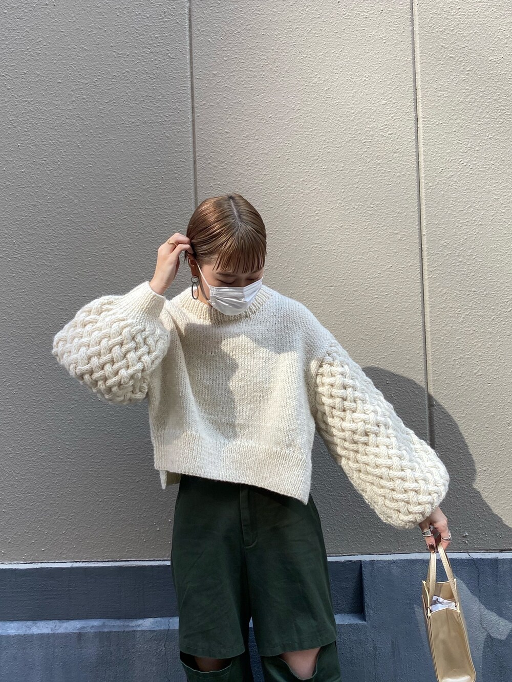 グリーン系のチノパンツ、ホワイト系のニット/セーターを着用したレディースの秋コーディネートの2枚目の写真