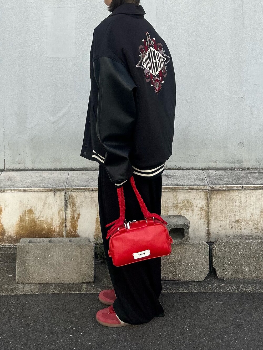 ブラック系のブルゾン、レッド系のハンドバッグを着用したレディースの冬コーディネートの2枚目の写真