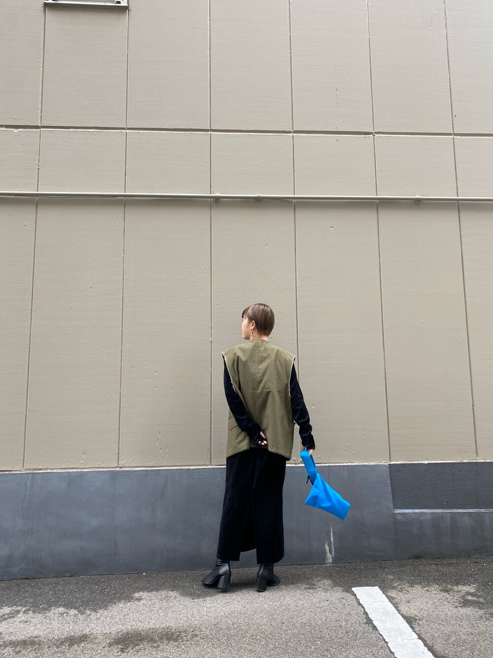 グリーン系のベストを着用したレディースの秋コーディネートの2枚目の写真