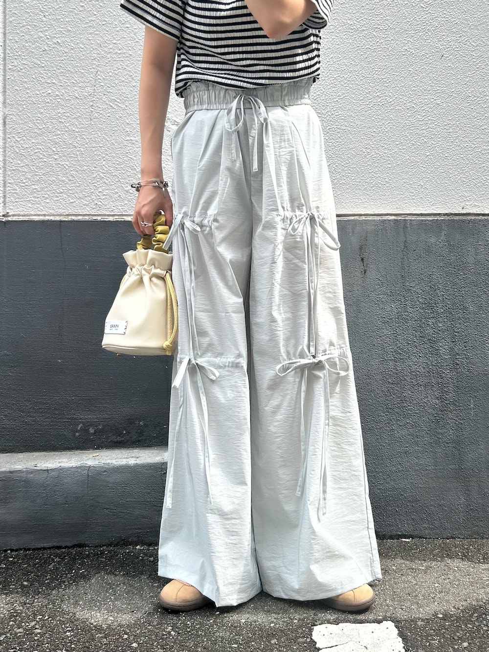 グレー系のその他パンツ、ブラック系のTシャツ/カットソー、ホワイト系のハンドバッグを着用したレディースの夏コーディネートの2枚目の写真