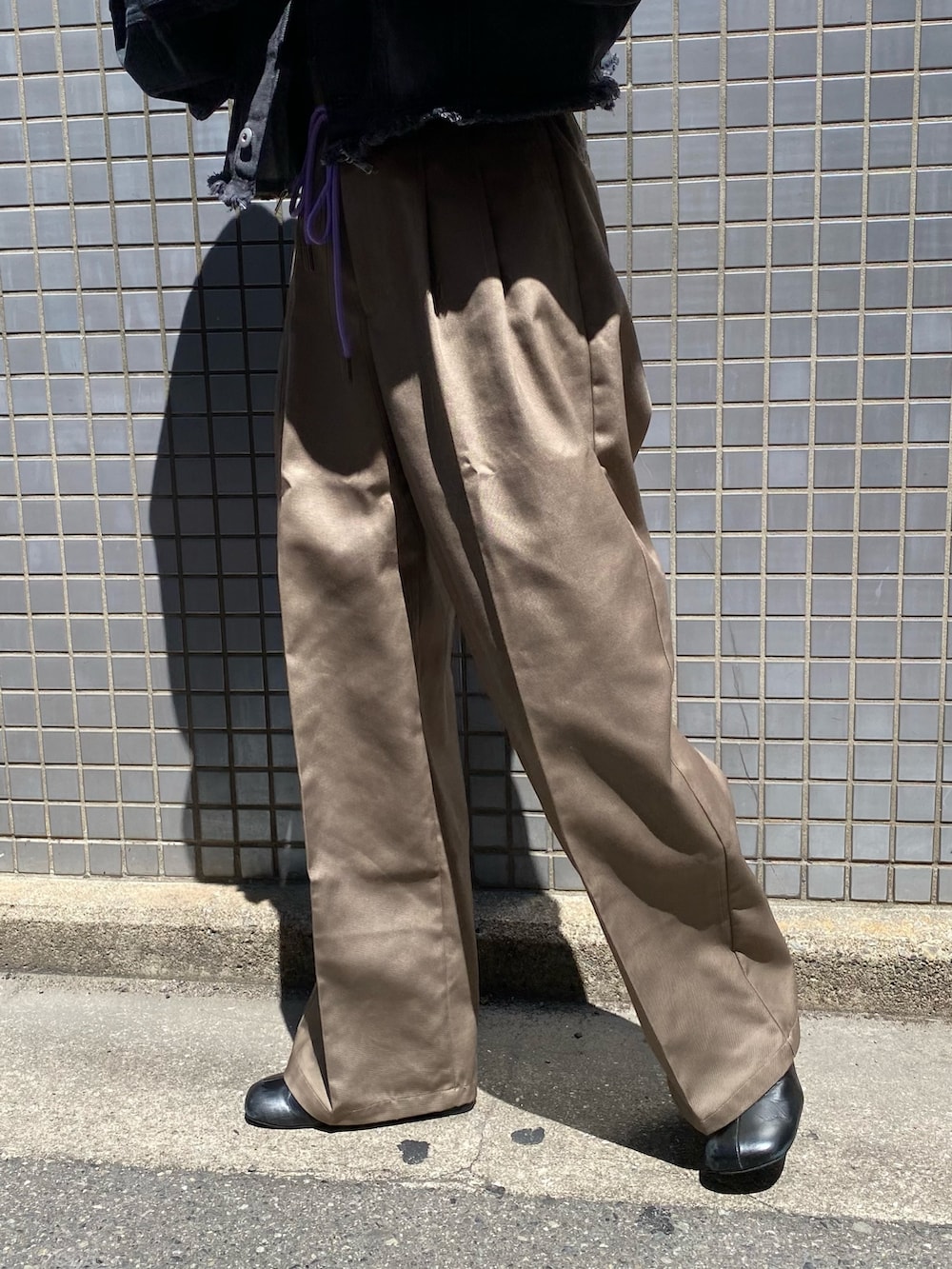 ブラック系のデニムジャケット、グレー系のチノパンツを着用したレディースの夏コーディネートの4枚目の写真