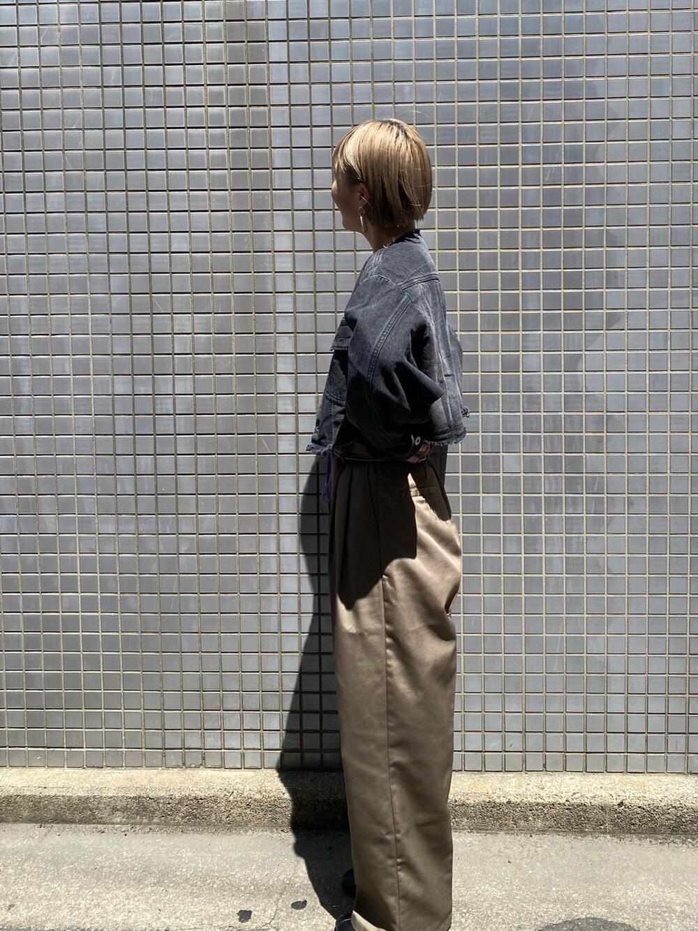 ブラック系のデニムジャケット、グレー系のチノパンツを着用したレディースの夏コーディネートの3枚目の写真