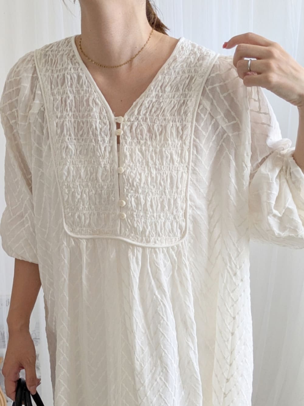 ブラック系のブーツ、ホワイト系のワンピース、ホワイト系のキャップを着用したレディースの夏コーディネートの4枚目の写真