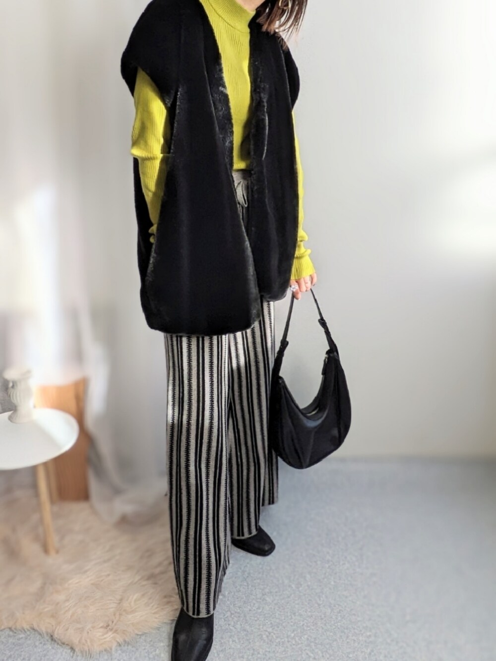 グレー系のその他パンツ、ブラック系のベスト、イエロー系のニット/セーターを着用したレディースの秋コーディネートの3枚目の写真