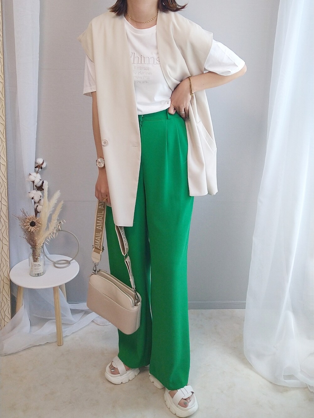 ホワイト系のTシャツ/カットソー、グリーン系のスラックス、ベージュ系のショルダーバッグを着用したレディースの春コーディネートの3枚目の写真