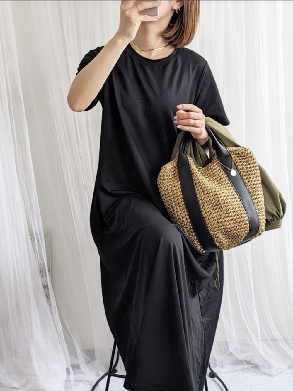 グリーン系のブルゾン、ブラック系のワンピース、ブラック系のショルダーバッグを着用したレディースの春コーディネートの2枚目の写真