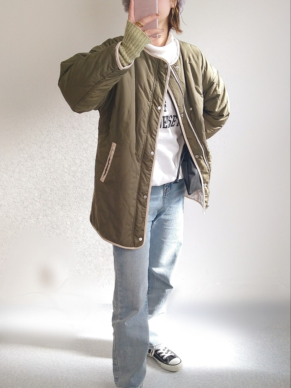 グリーン系のブルゾン、ホワイト系のスウェット、ブラック系のショルダーバッグを着用したレディースの冬コーディネートの2枚目の写真