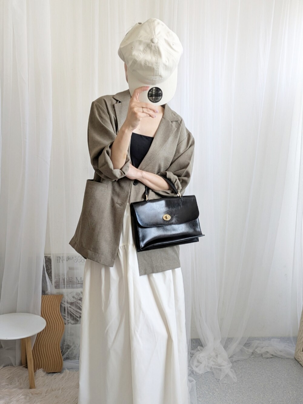 ブラック系のショルダーバッグ、ホワイト系のキャップを着用したレディースの夏コーディネートの3枚目の写真