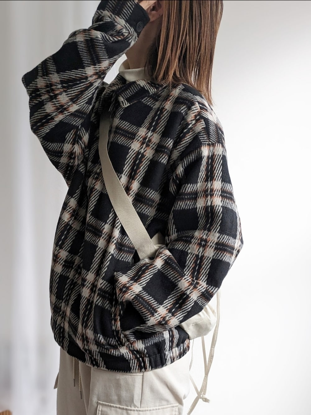 ベージュ系のショルダーバッグ、ブラック系のブルゾン、ホワイト系のその他パンツを着用したレディースの冬コーディネートの4枚目の写真