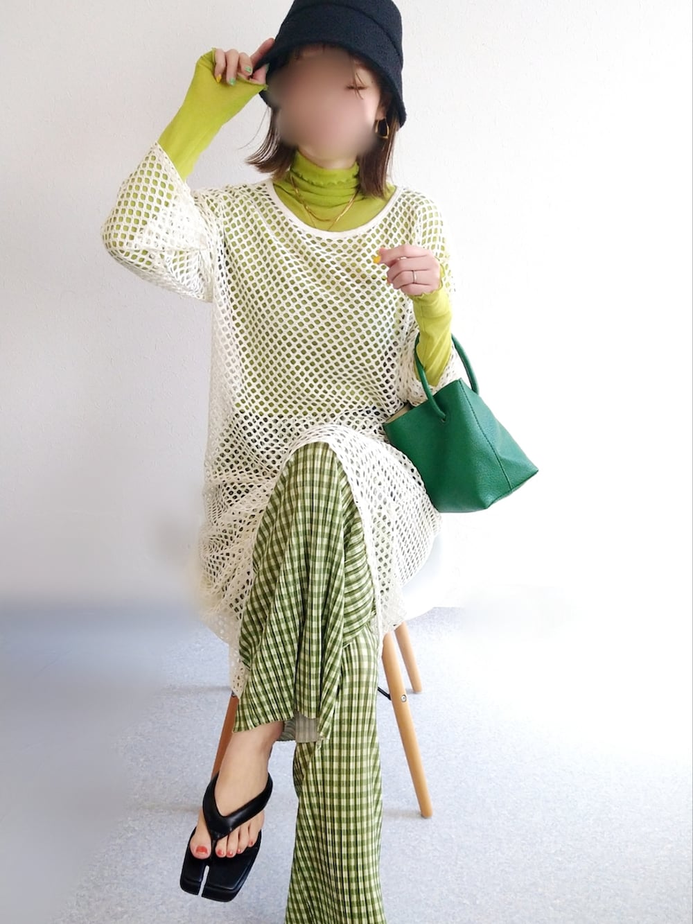 グリーン系のハンドバッグ、ブラック系のサンダルを着用したレディースの春コーディネートの2枚目の写真