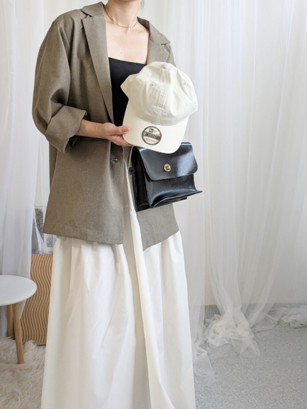 ブラック系のショルダーバッグ、ホワイト系のキャップを着用したレディースの夏コーディネートの2枚目の写真