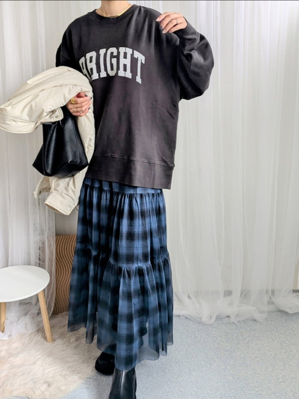 ブルー系のスカート、ブラック系のハンドバッグ、グレー系のスウェットを着用したレディースの秋コーディネートの2枚目の写真