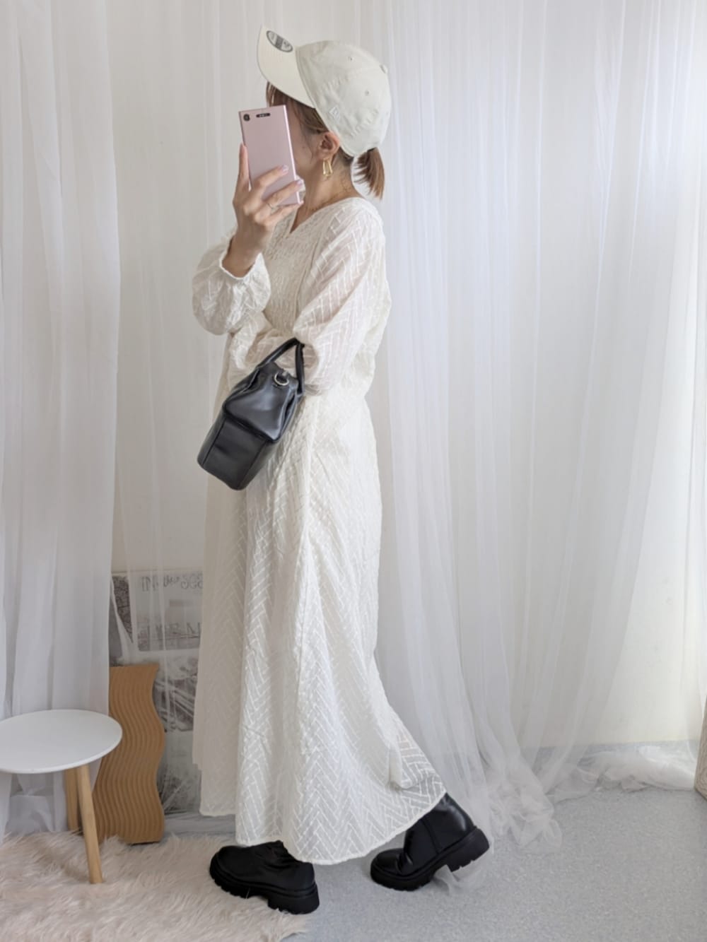 ブラック系のブーツ、ホワイト系のワンピース、ホワイト系のキャップを着用したレディースの夏コーディネートの2枚目の写真