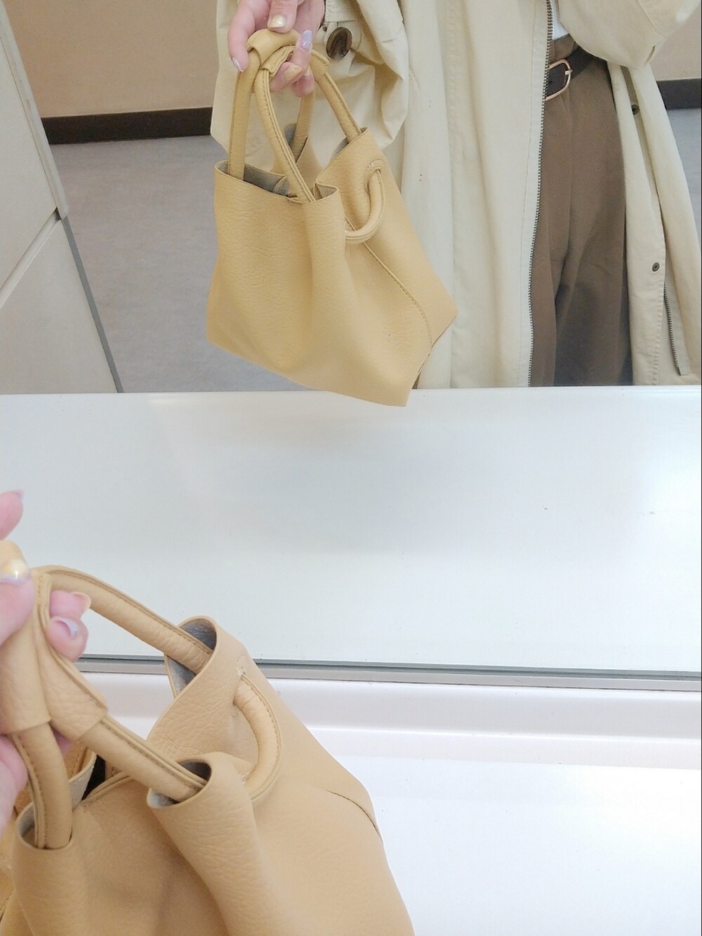 イエロー系のハンドバッグ、ブラウン系のパンツ、ブラウン系のベルトを着用したレディースの春コーディネートの2枚目の写真