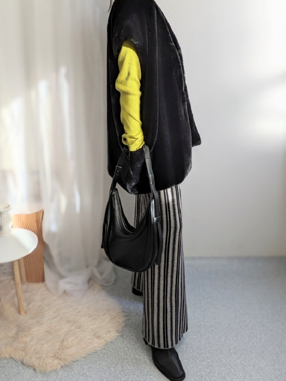 グレー系のその他パンツ、ブラック系のベスト、イエロー系のニット/セーターを着用したレディースの秋コーディネートの4枚目の写真
