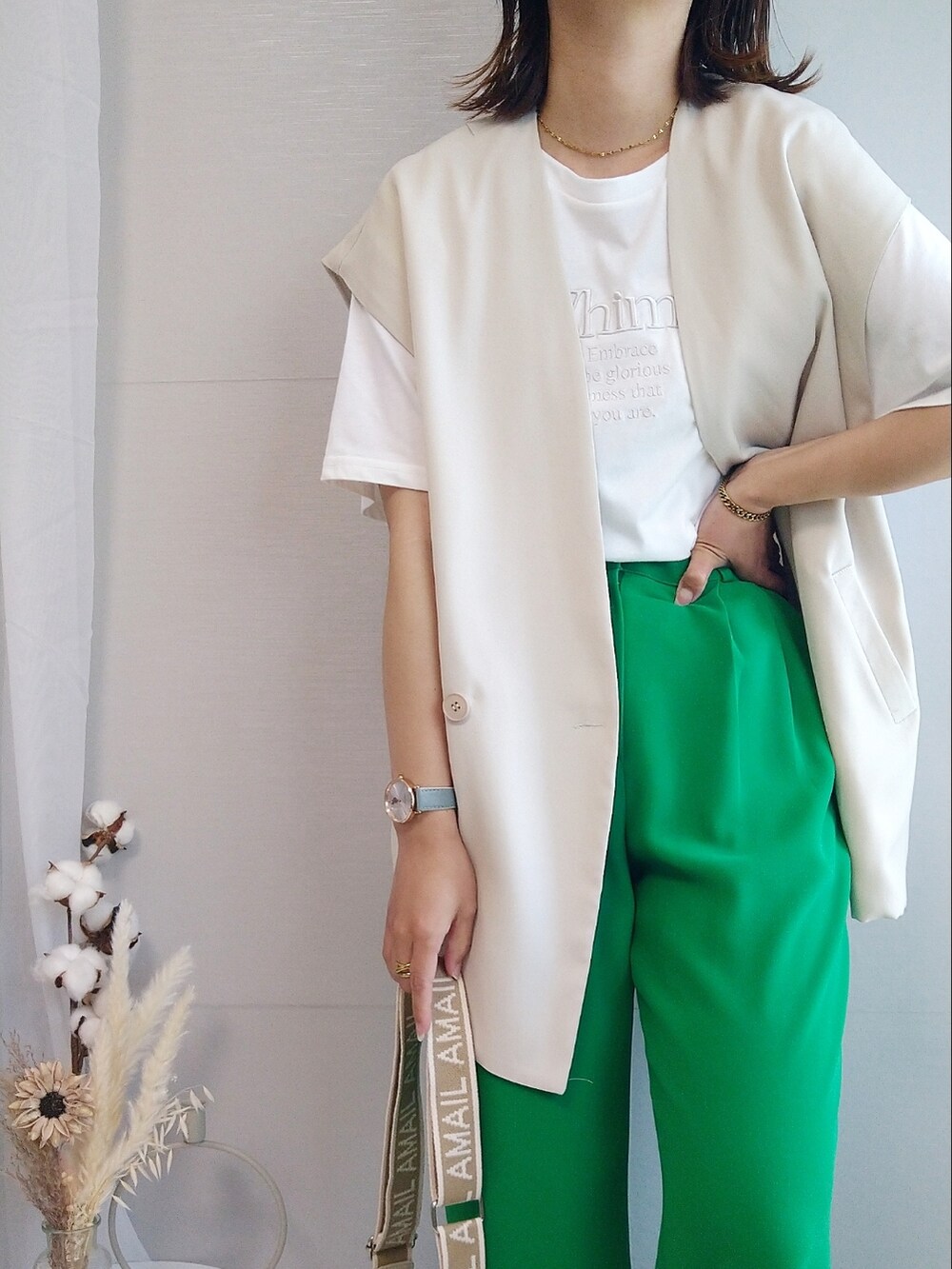 ホワイト系のTシャツ/カットソー、グリーン系のスラックス、ベージュ系のショルダーバッグを着用したレディースの春コーディネートの2枚目の写真
