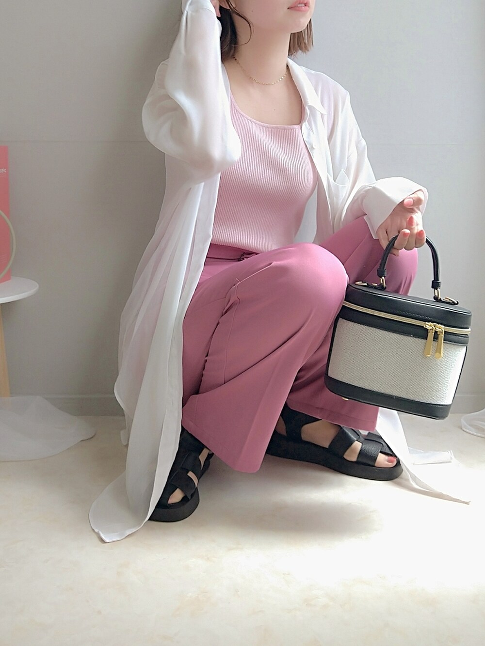 ピンク系のトップス、ピンク系のスラックス、ブラック系のサンダルを着用したレディースの春コーディネートの2枚目の写真