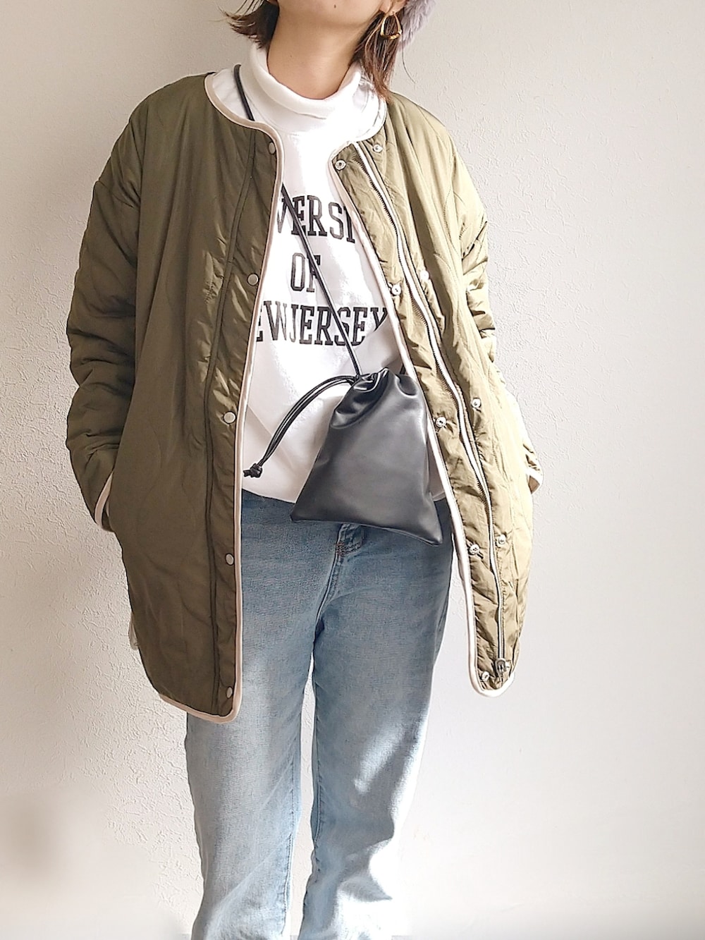 グリーン系のブルゾン、ホワイト系のスウェット、ブラック系のショルダーバッグを着用したレディースの冬コーディネートの3枚目の写真