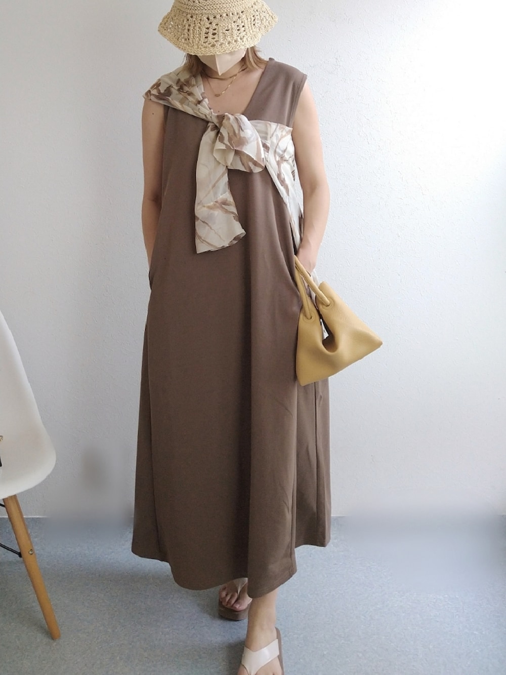 ブラウン系のジャンパースカート、イエロー系のハンドバッグ、ホワイト系のサンダルを着用したレディースの夏コーディネートの3枚目の写真