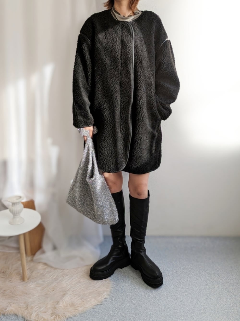 シルバー系のショルダーバッグ、ブラック系のノーカラーコート、ブラック系のその他パンツを着用したレディースの冬コーディネートの3枚目の写真