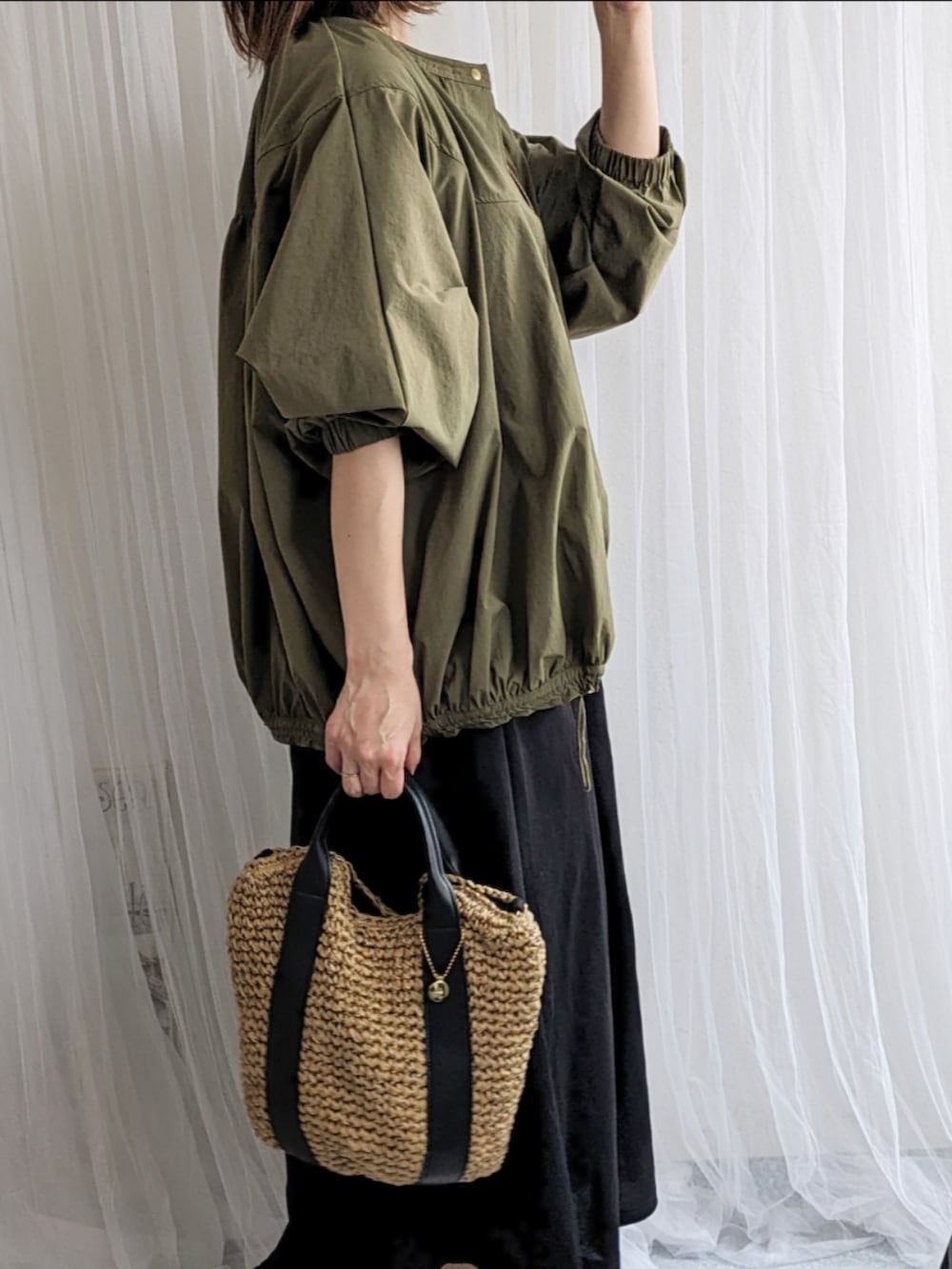 グリーン系のブルゾン、ブラック系のワンピース、ブラック系のショルダーバッグを着用したレディースの春コーディネートの3枚目の写真