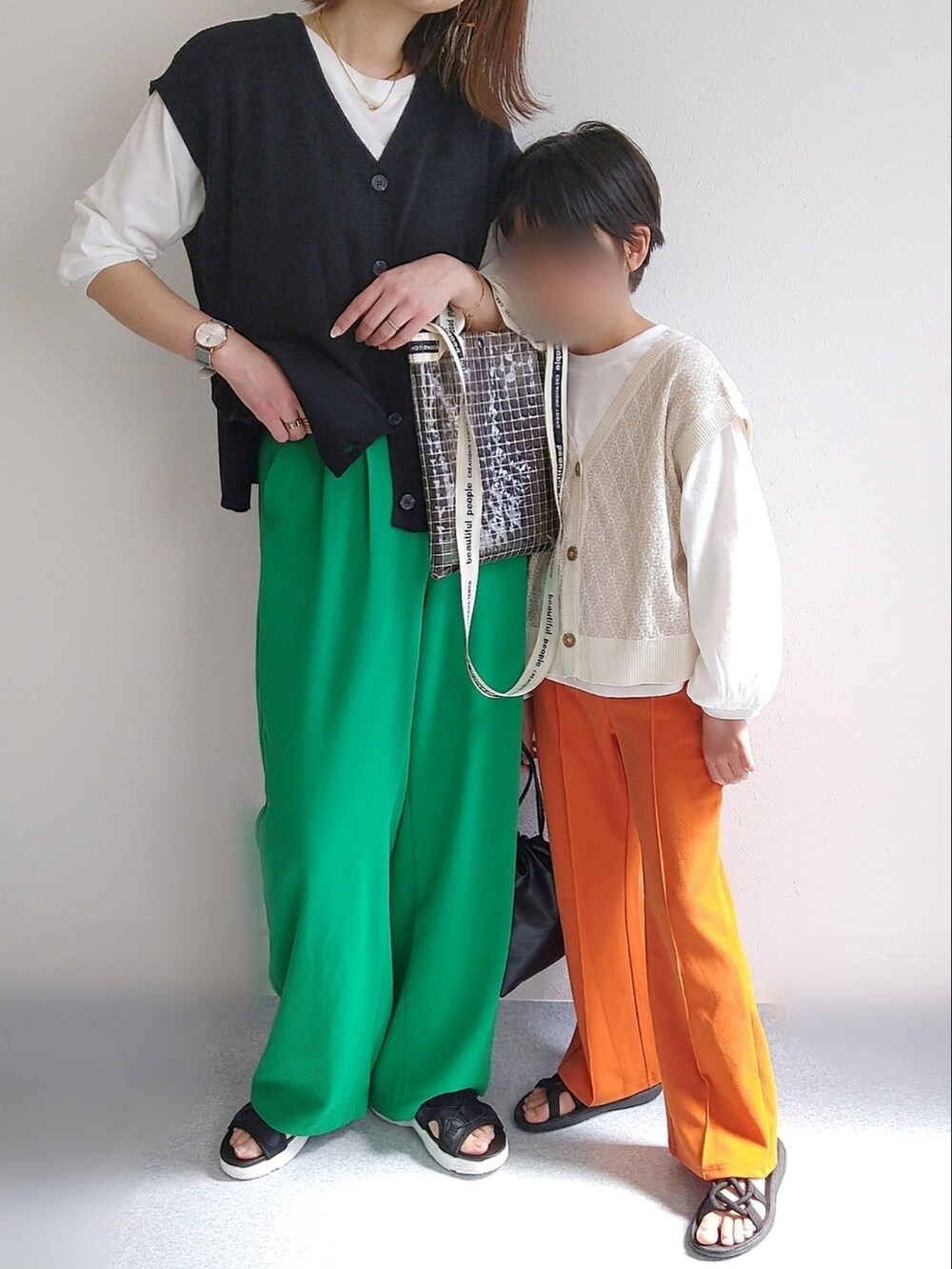 ホワイト系のマウンテンパーカー、ブラック系のアンサンブル、ブラック系のショルダーバッグを着用したキッズの春コーディネートの2枚目の写真