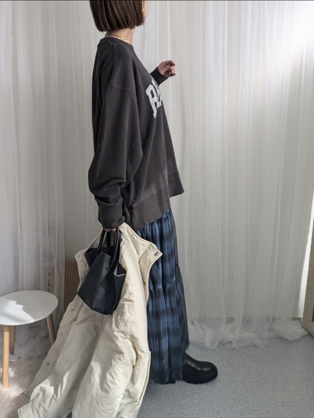 ブルー系のスカート、ブラック系のハンドバッグ、グレー系のスウェットを着用したレディースの秋コーディネートの4枚目の写真