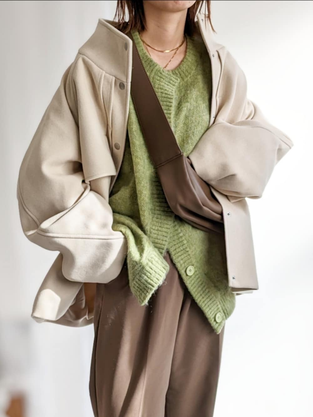 ブラウン系のショルダーバッグ、ホワイト系のその他アウター、グリーン系のカーディガン/ボレロを着用したレディースの秋コーディネートの2枚目の写真