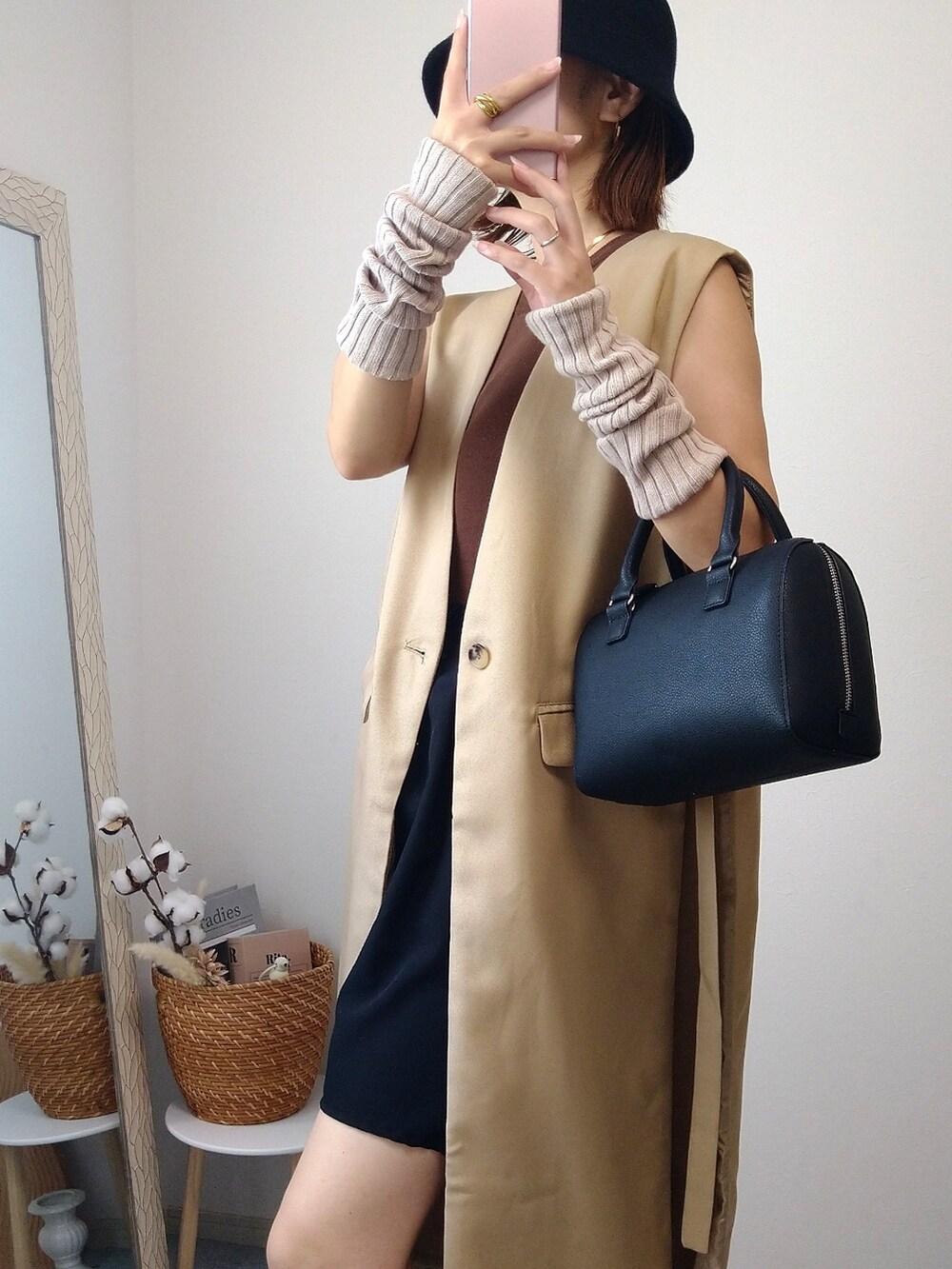 ベージュ系のベスト、ブラック系のバッグ、ブラック系のブーツを着用したレディースの秋コーディネートの2枚目の写真