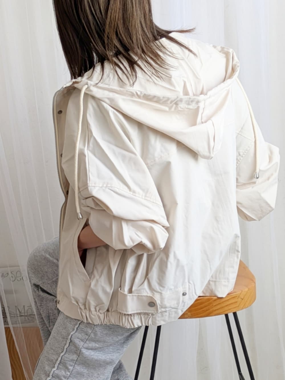 ホワイト系のマウンテンパーカー、ブラック系のTシャツ/カットソー、グレー系のスウェットパンツを着用したレディースの春コーディネートの2枚目の写真