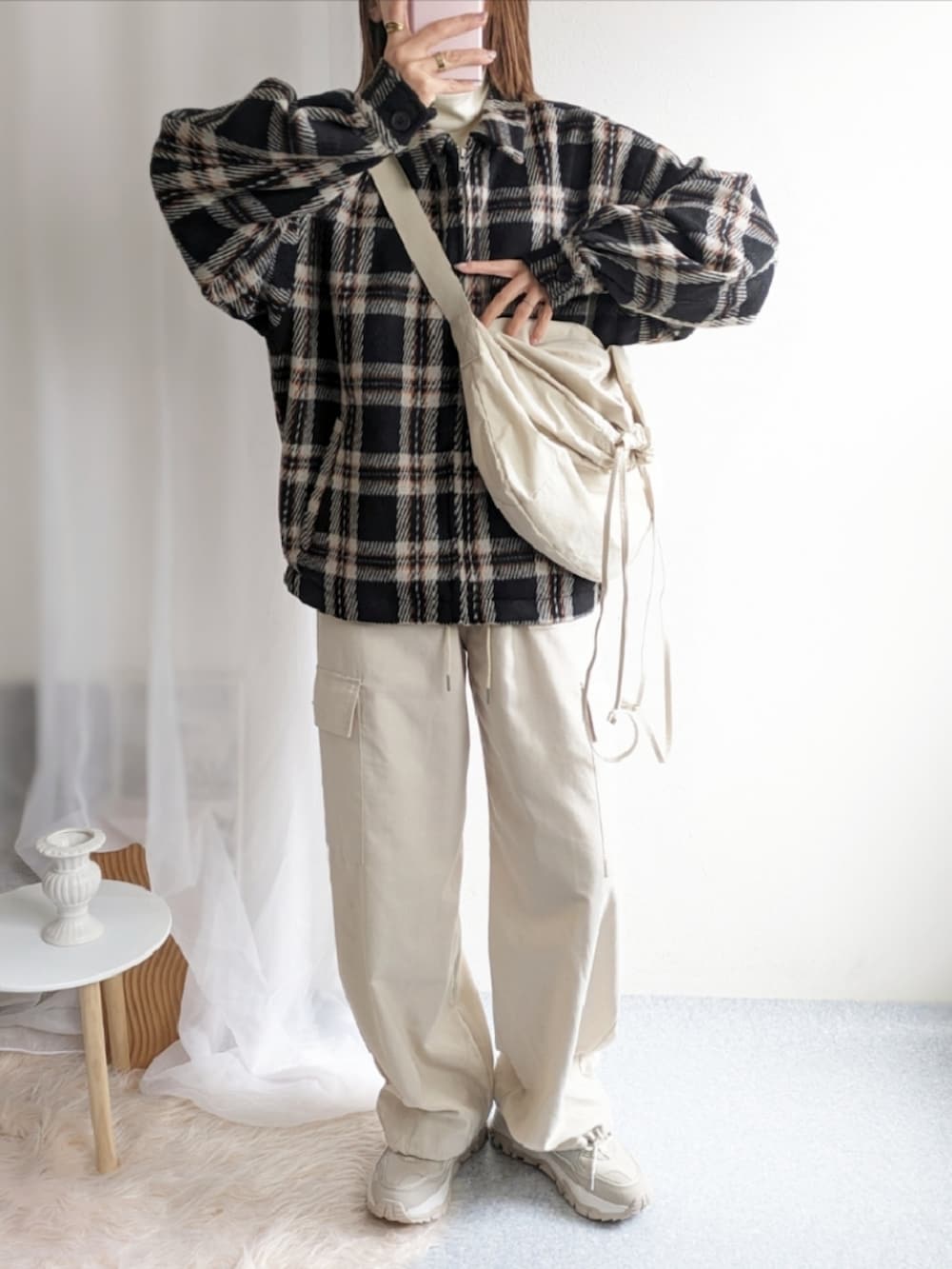 ベージュ系のショルダーバッグ、ブラック系のブルゾン、ホワイト系のその他パンツを着用したレディースの冬コーディネートの2枚目の写真