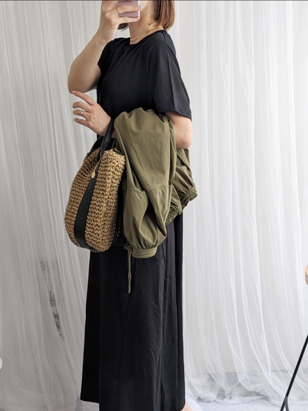 グリーン系のブルゾン、ブラック系のワンピース、ブラック系のショルダーバッグを着用したレディースの春コーディネートの5枚目の写真