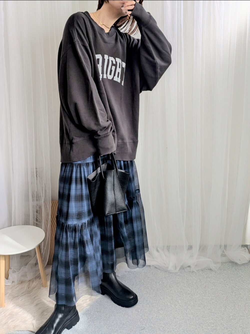 ブルー系のスカート、ブラック系のハンドバッグ、グレー系のスウェットを着用したレディースの秋コーディネートの3枚目の写真