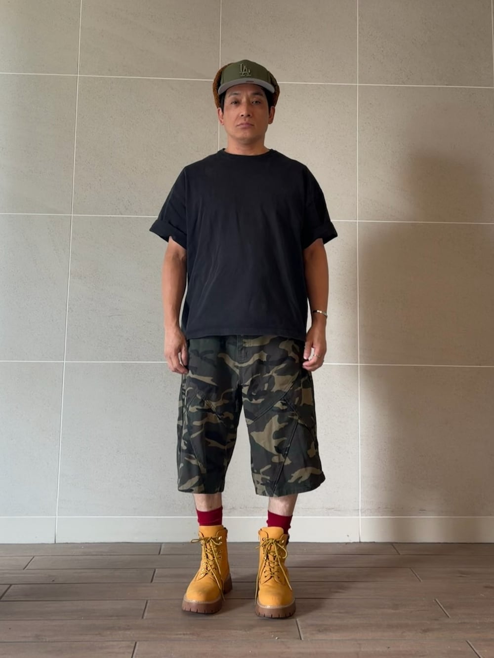 ブラック系のTシャツ/カットソー、グリーン系のカーゴパンツ、イエロー系のブーツを着用したメンズの秋コーディネートの2枚目の写真