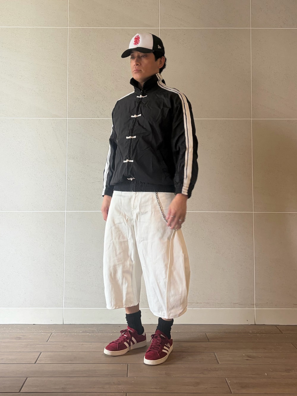 レッド系のスニーカー、ブラック系のジャージ、ホワイト系のパンツを着用したメンズの秋コーディネートの2枚目の写真