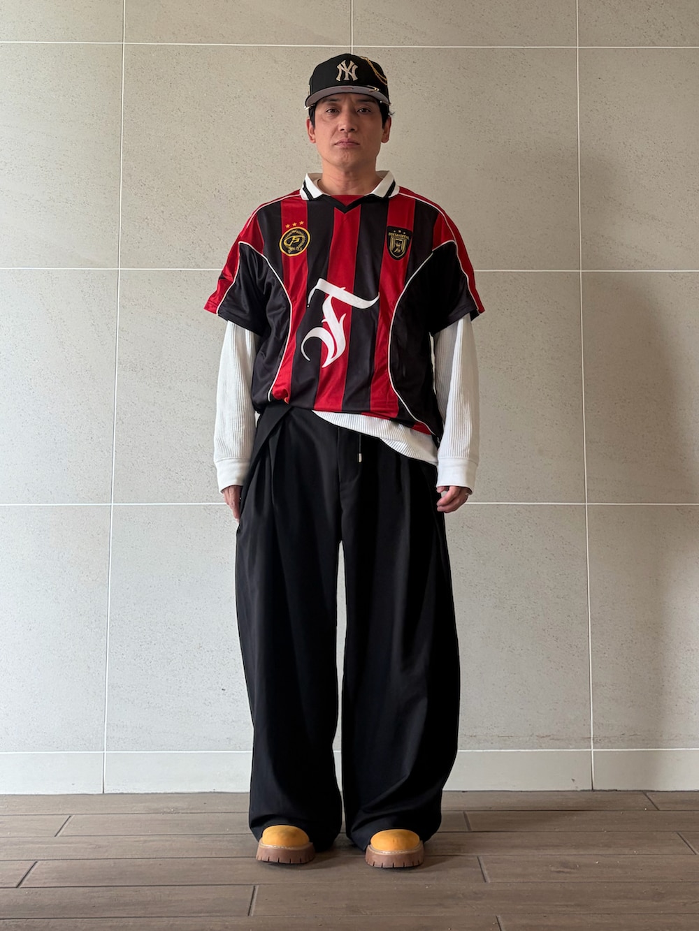 イエロー系のブーツ、ブラック系のスラックス、ホワイト系のTシャツ/カットソーを着用したメンズの春コーディネートの2枚目の写真