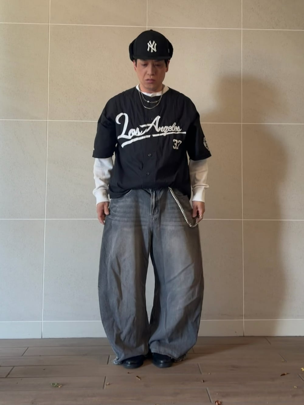 ブラック系のスタジャン、グレー系のデニムパンツ、ブラック系のドレスシューズを着用したメンズの春コーディネートの2枚目の写真