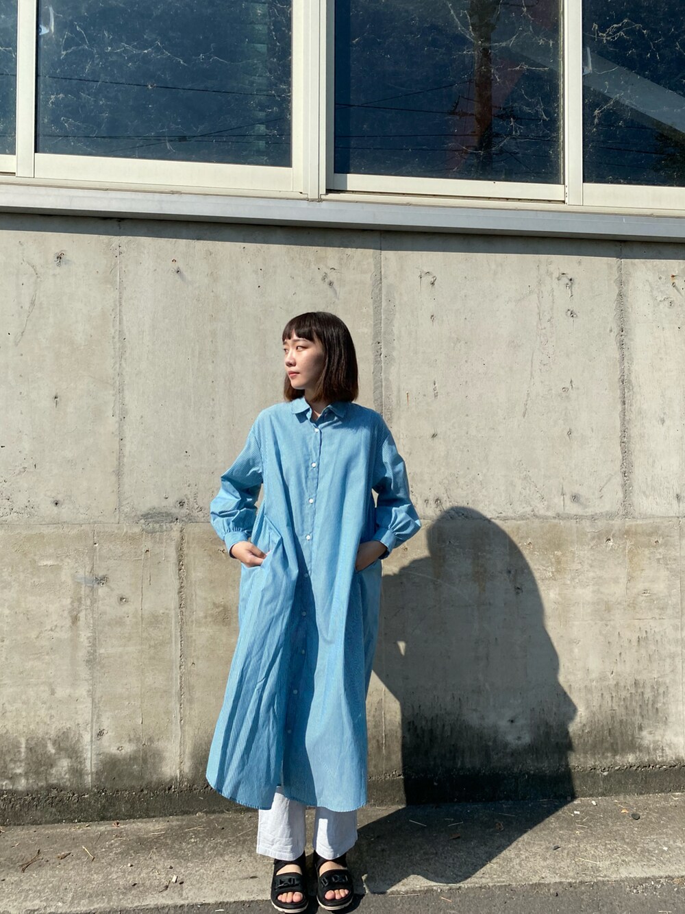 ブラック系のサンダル、グリーン系のシャツワンピース、ホワイト系のパンツを着用したレディースの秋コーディネートの2枚目の写真