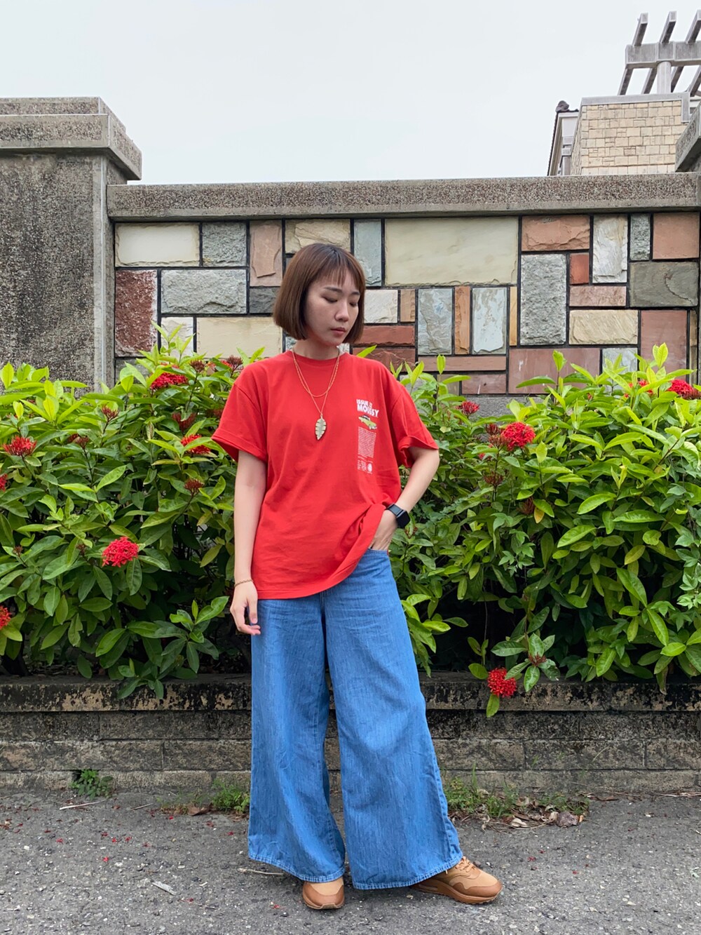 レッド系のTシャツ/カットソー、ブルー系のデニムパンツ、ブラウン系のスニーカーを着用したレディースの春コーディネートの2枚目の写真