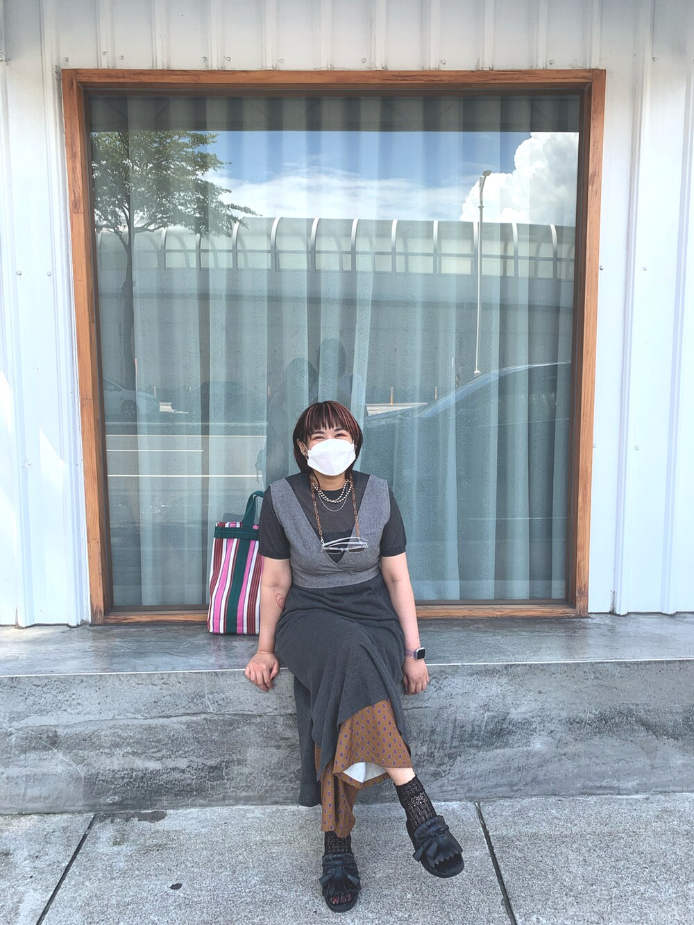 グレー系のワンピース、ブラック系のサンダル、レッド系のトートバッグを着用したレディースの夏コーディネートの2枚目の写真