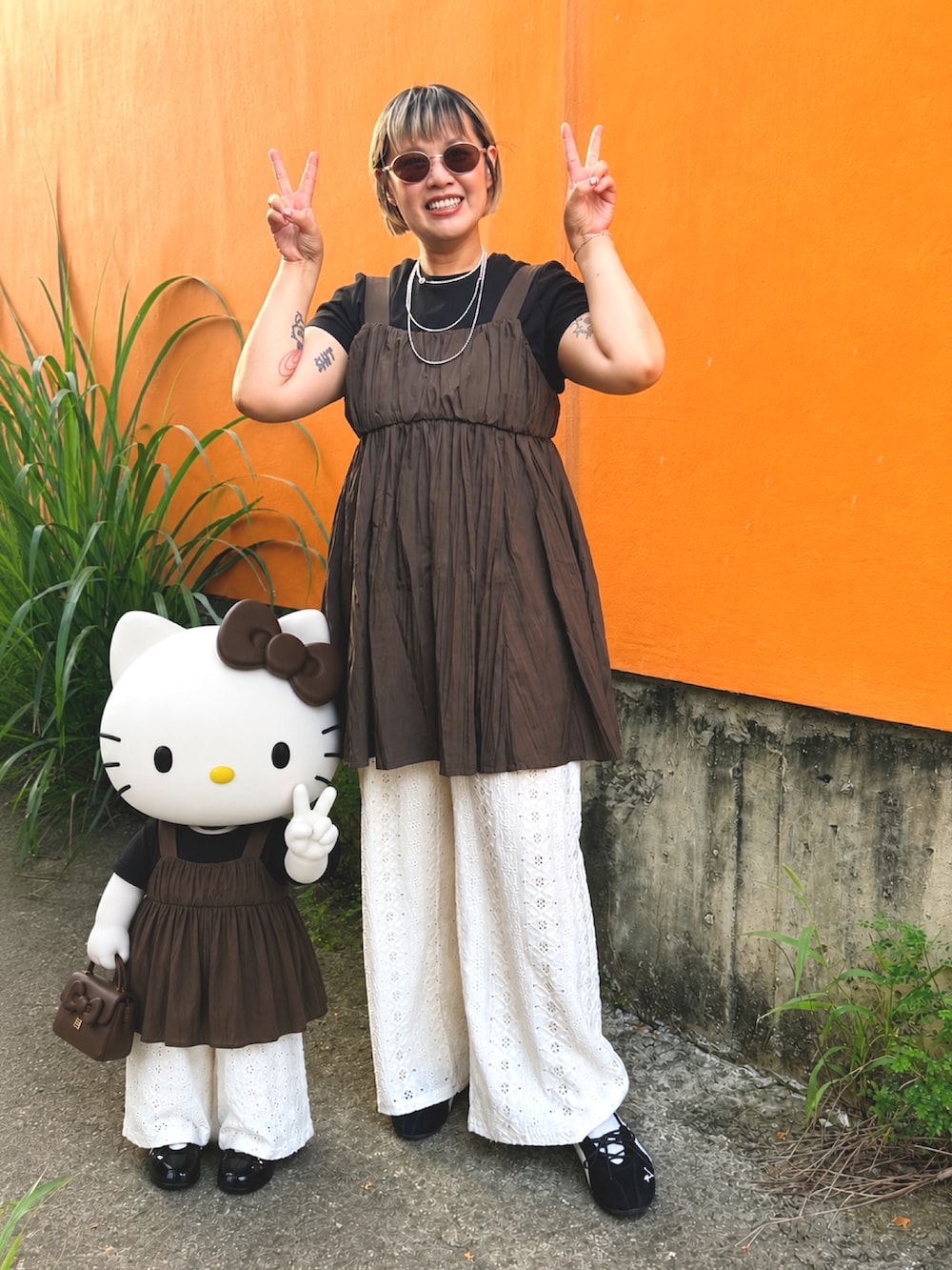 ブラウン系のワンピース、ブラック系のスニーカー、シルバー系のネックレスを着用したレディースの夏コーディネートの2枚目の写真