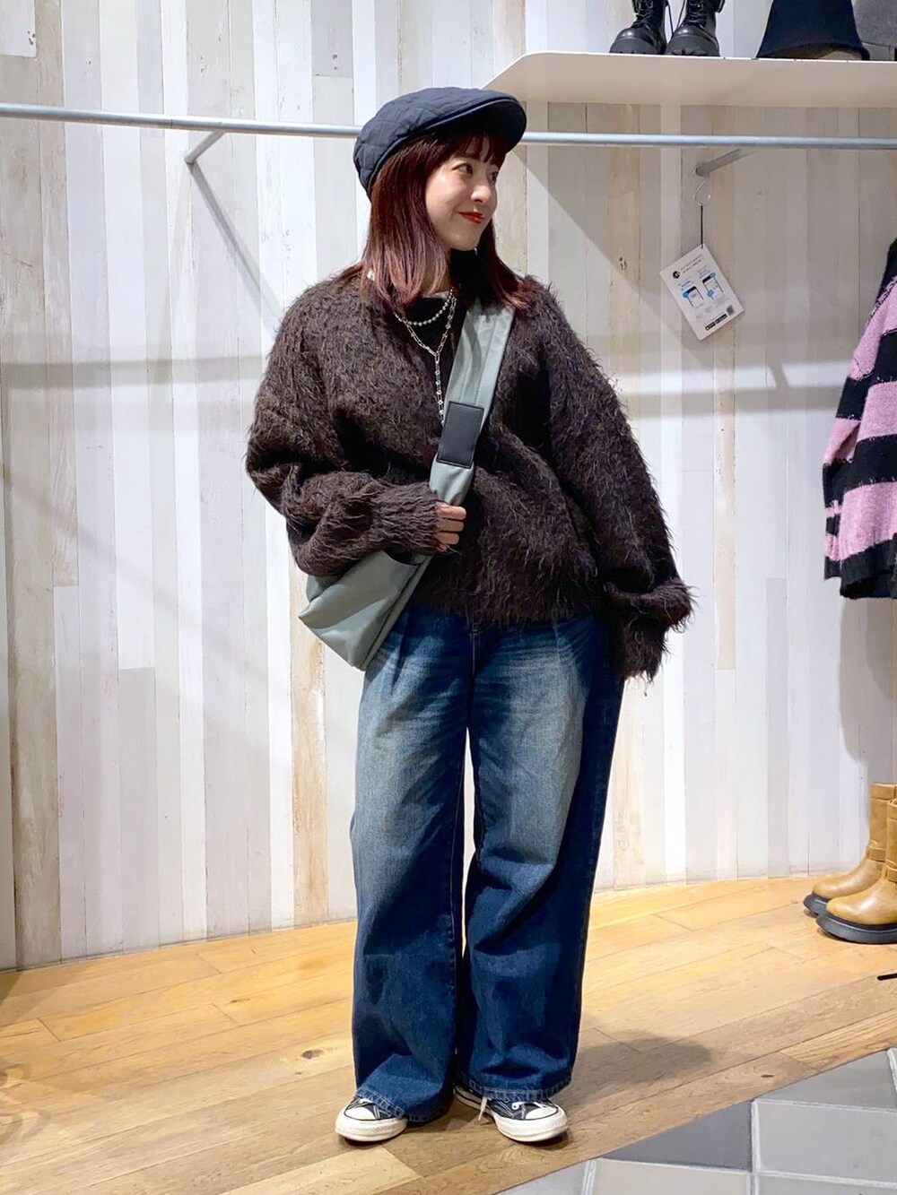 グリーン系のボディバッグ/ウエストポーチ、ブルー系のデニムパンツ、ブラウン系のニット/セーターを着用したレディースの秋コーディネートの4枚目の写真